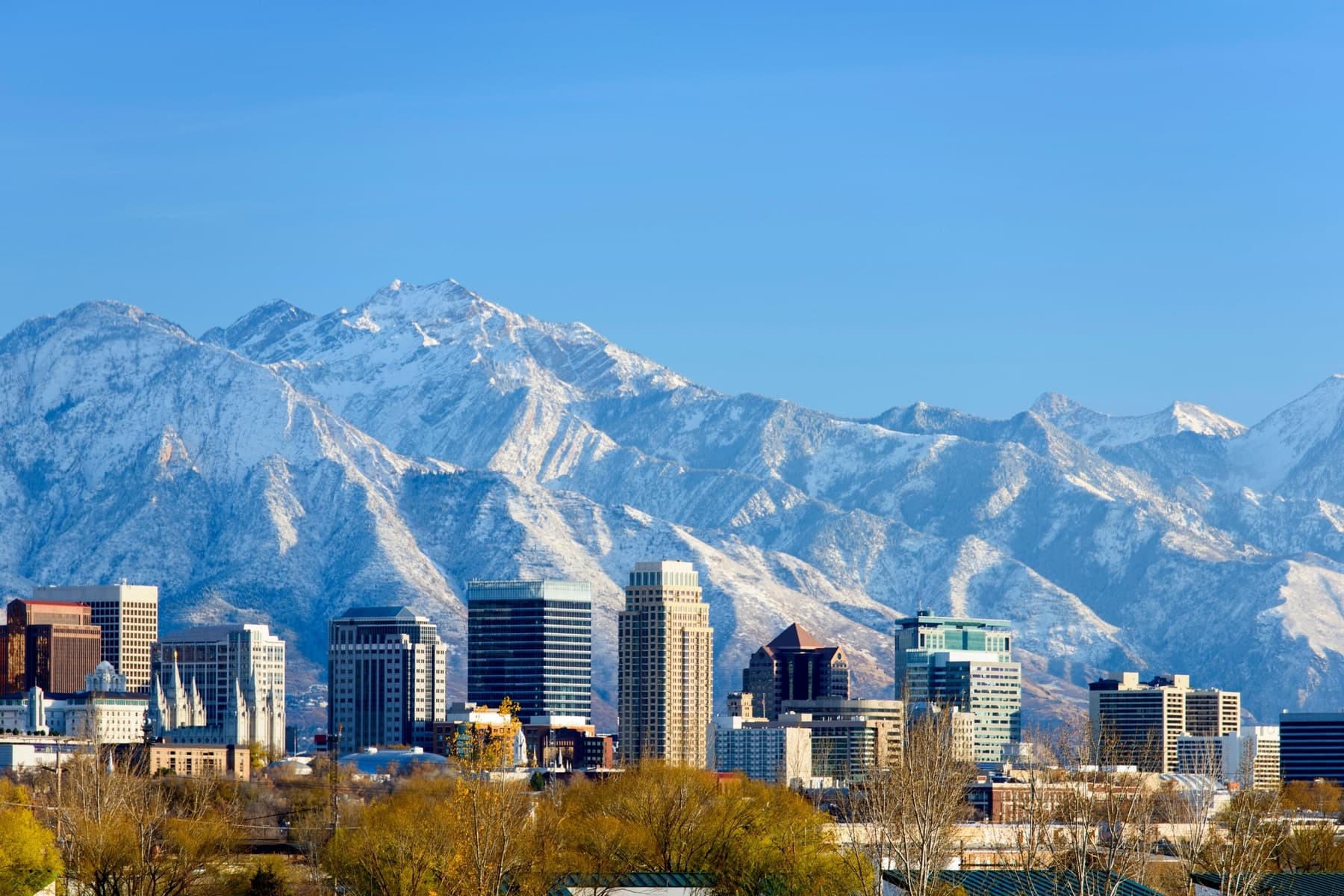 Salt Lake City skyline with the Wasatch range as a backdrop, warm daylight.